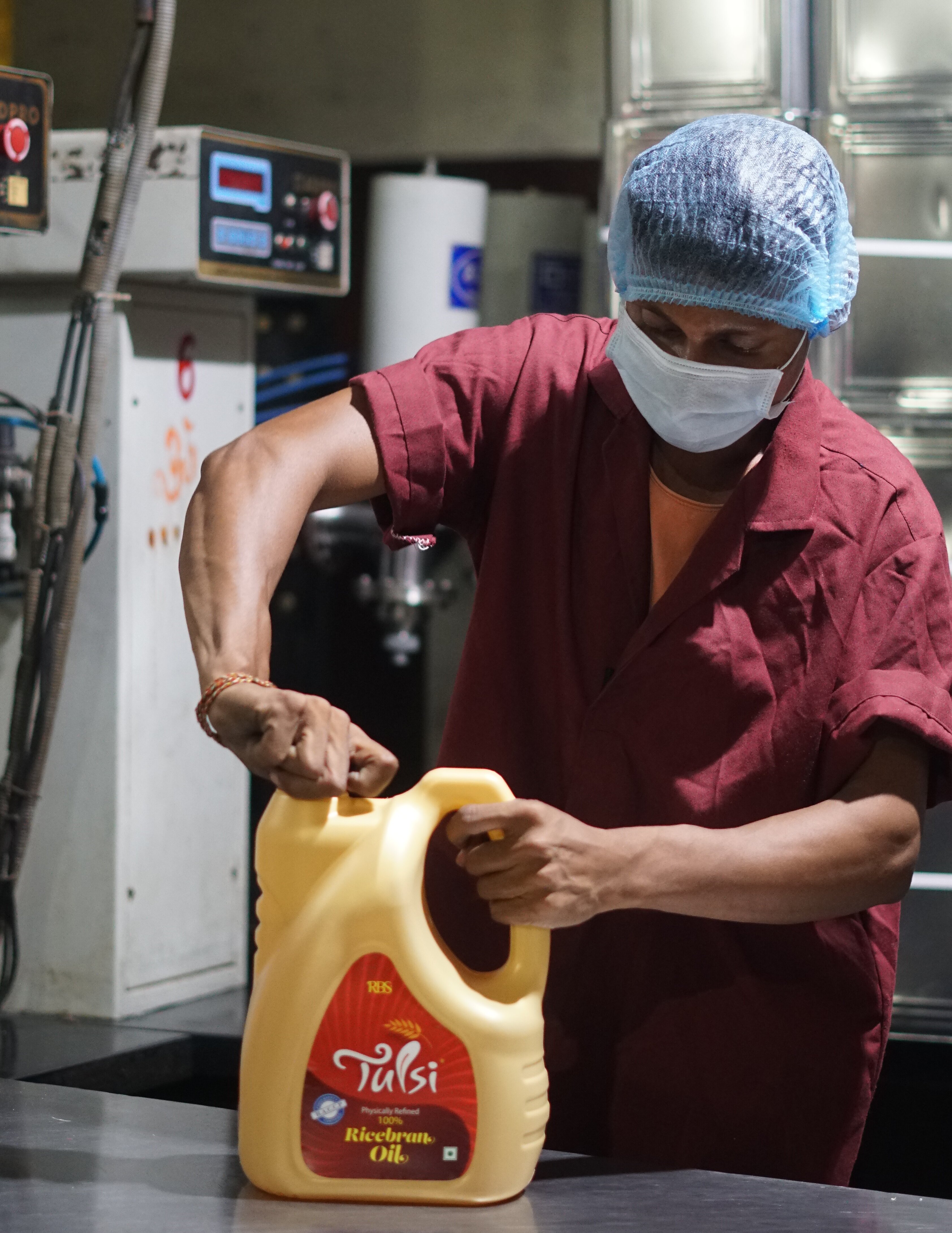 A worker capping a bottle of Tulsi rice bran oil on the filling line